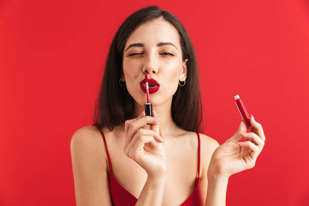 Foto mladé krásné ženy představují samostatný hospodářství lip gloss dělá make-up. - Fotografie, Obrázek