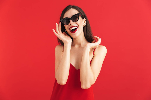 Image of happy smiling beautiful young woman posing isolated over red background. - Foto, afbeelding