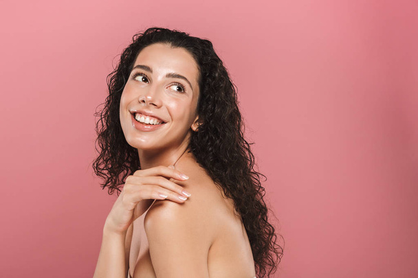 Beauty portrait of a smiling young topless woman with curly brunette hair posing over pink background - Foto, immagini