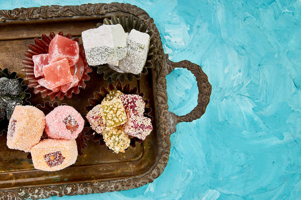 Set of various Turkish delight in a copper plate  on metal tray blue backgroun - Foto, Imagen