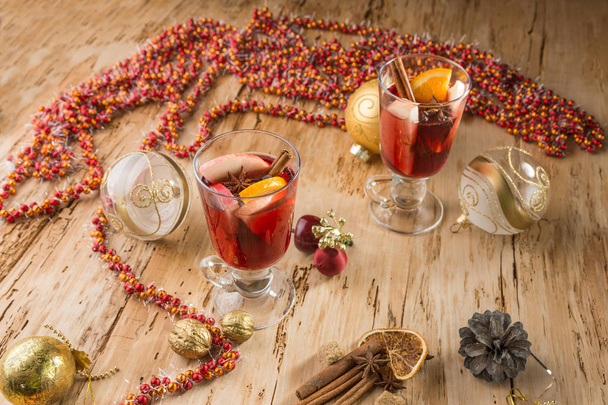 Christmas mulled red wine with spices and fruits on a wooden rustic table. Traditional hot drink at Christmas time - Photo, image