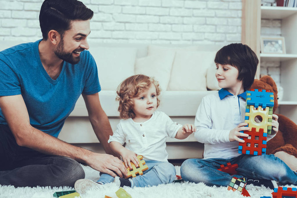 Smiling Kids. Father. Toys.Baby with Bright Hair. Spends Time. Happy Together. Leisure Time. Father Two Boys. Man. Smile. Home Time. Two Boys. Plays Games. Teddy Bear. Cars. Holidays. - Photo, image