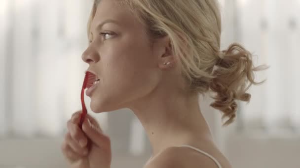 Молода красива біла жінка чистить зуби і посміхається на камеру
 - Кадри, відео