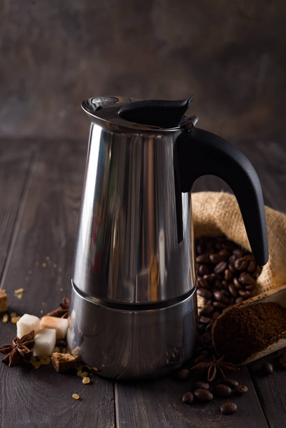 Geysir-Kaffeemaschine auf dem Hintergrund einer Tüte Kaffee und Zuckerkörner auf dunklem Holzhintergrund, Kopierraum - Foto, Bild