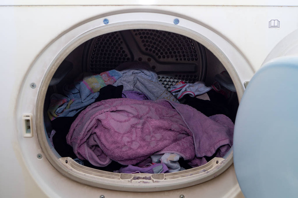 Washing machine porthole in the foreground with laundry inside - Photo, Image