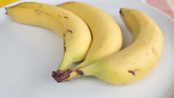 three bananas on a white rotating plate - Imágenes, Vídeo