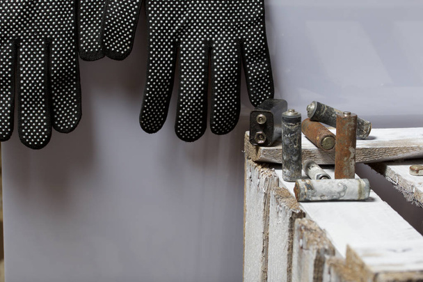 Used finger-wound batteries covered with corrosion. They lie on a wooden box. Next working gloves. Recycling. - 写真・画像