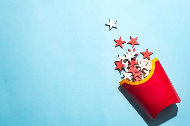 Boîte à frites vierge avec étoiles en bois coloré du Nouvel An sur un fond de papier bleu, pose plate avec espace de copie. Concept commander un repas pour un Noël
 - Photo, image
