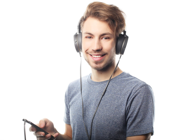 Man holding mobile phone and lictening to music over white background - Φωτογραφία, εικόνα