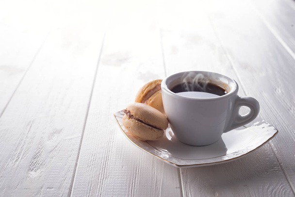 Smaczny słodki macarons i filiżankę kawy. Makaroniki na białym tle drewnianych. Miejsce - Zdjęcie, obraz