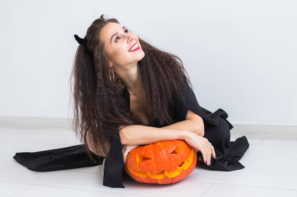 Halloween en maskerade concept - mooie jonge vrouw poseren met pompoen Jack-o-lantaarn. - Foto, afbeelding