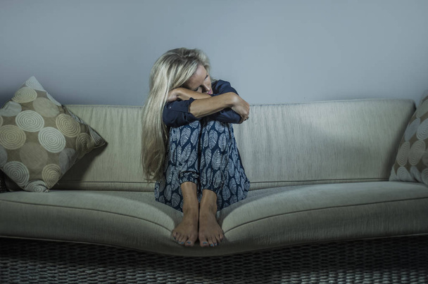 lifestyle dramatic portrait of attractive and sad woman feeling frustrated and anxious sitting at home sofa couch depressed suffering anxiety crisis and depression problem thoughtful and desperate - Photo, image