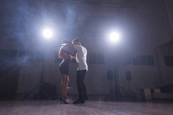 コンサート光と煙の下で暗い部屋で実行する巧みなダンサー。芸術的、感情的なコンテンポ ラリー ダンスを実行する官能的なカップル - 写真・画像