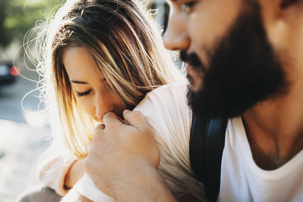 Beautiful blond woman embracing bearded man with love and eyes closed sitting in sunlight - Foto, Bild