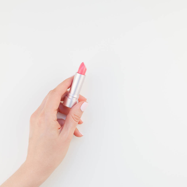 Woman hand with pastel manicure polish holding pink lipstick isolated on white background with copy space. Square template for feminine beauty blog social media - Photo, Image
