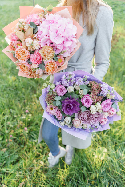 two beautiful spring bouquet. Young girl holding a flowers arrangements with various of colors. Bright dawn or sunset sun - 写真・画像
