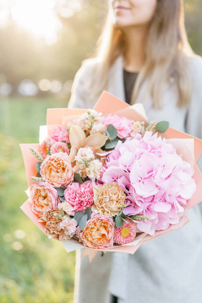 beautiful spring bouquet. Young girl holding a flowers arrangement with various of colors. Bright dawn or sunset sun - Photo, Image