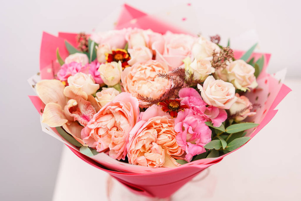szép tavaszi csokor. virág elrendezése különböző színű üveg vázában, rózsaszín asztalra. világos szoba, fehér fal. - Fotó, kép