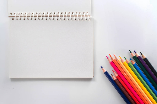 notepad with color pencil on white table view from above - Фото, изображение