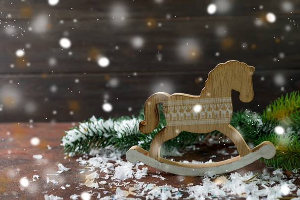 Игрушечный деревянный качающийся конь как новогодние украшения со снегом и деревом на деревянном фоне
 - Фото, изображение