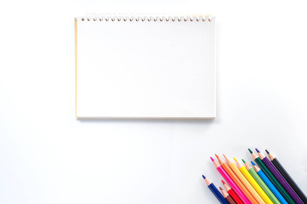 bloco de notas com lápis de cor na vista da tabela branca de cima
 - Foto, Imagem