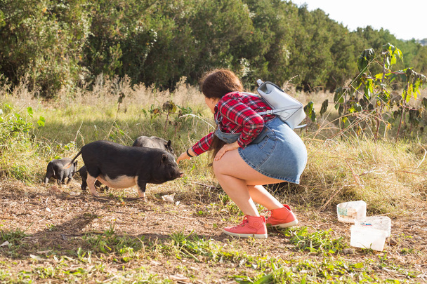 Happy young woman plays with little wild boars on nature. - Photo, Image