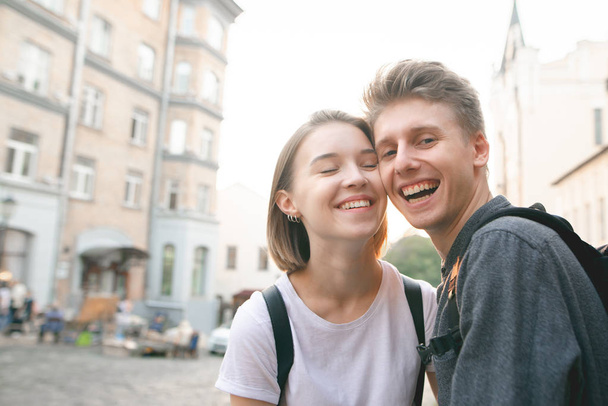 Smiling happy couple on the background of the sunset and old architecture. Beautiful guy and girl smiling at sunset and looking at the camera. Positive couple in love outdoor portrait. - Fotoğraf, Görsel