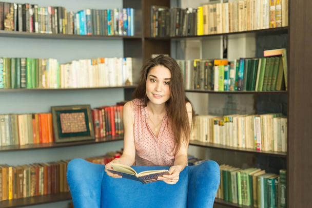 Osób, edukacji i wiedzy koncepcja - Kobieta, czytanie książki w bibliotece - Zdjęcie, obraz