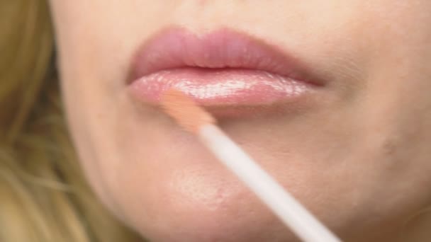Super close-up, slow-motion, 4k. een vrouw is het schilderen van lippen met lipgloss. lip make-up, dermatologische ziekte op de huid van de lippen. Fox vossen korrels - Video