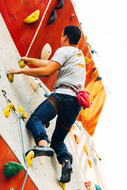 Człowiek wspinaczka na sztucznej ścianie wspinaczkowej w siłowni bouldering - Zdjęcie, obraz