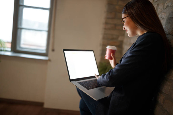 Girl in studio works at laptop and drinks coffee - Фото, зображення