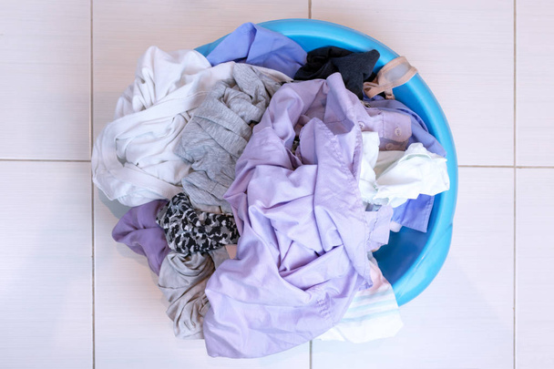 A basin full of dirty laundry on the bathroom floor, washing concept. - Photo, Image