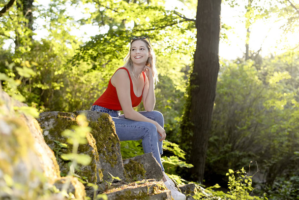 γελώντας νεαρή γυναίκα με γυαλιά ηλίου που κάθεται στο πάρκο - Φωτογραφία, εικόνα
