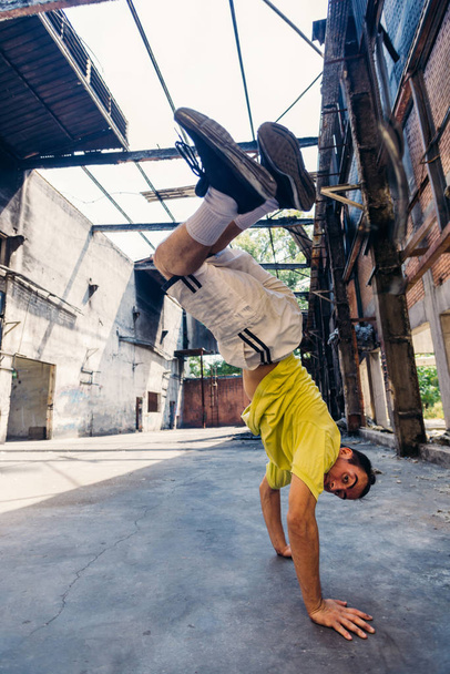 Parkour man in action while training handstand in abandoned factory - 写真・画像