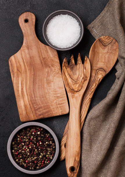 Olive wood kitchen utensils with chopping board on stone table background. Top view. - 写真・画像