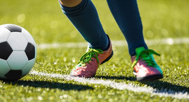 Εσωτερικη ποδόσφαιρο ποδόσφαιρο κλωτσάει τη μπάλα. Πόδια του ποδοσφαιριστή που τρέχει και να κλωτσάει την μπάλα ποδοσφαίρου για την πράσινη χλόη - Φωτογραφία, εικόνα
