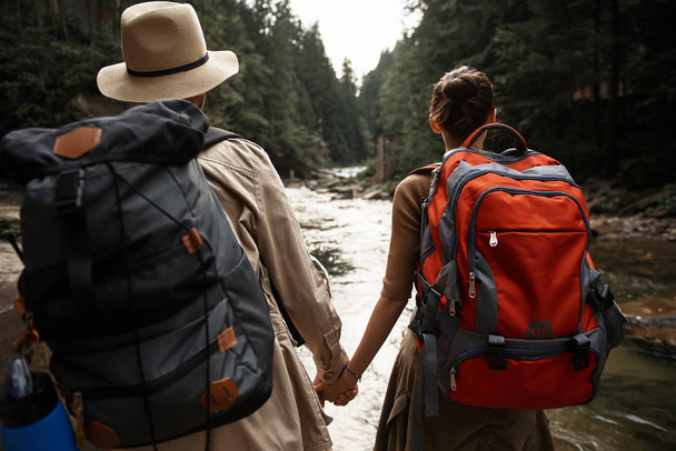 Active couple carrying backpacks and holding hands while traveling - Photo, Image