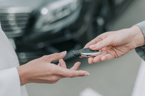 Γυναικείο χέρι δίνει το κλειδί από το σύγχρονο όχημα - Φωτογραφία, εικόνα