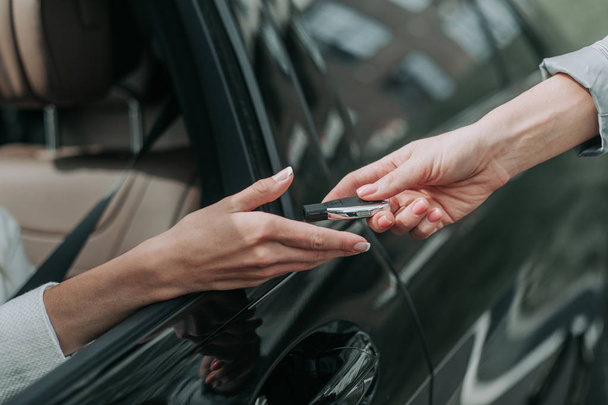 Woman hand taking key from automobile seller - Foto, afbeelding
