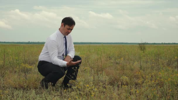Serious businessman in tie works in field and shows class - Footage, Video