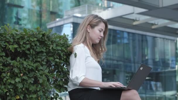 Young businesswoman working on laptop in city park business center - Video