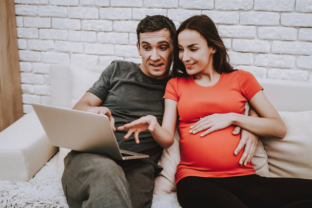 Sweet. Sofa. Husband and Pregnant Wife. Laptop. Sit. Together on Couch. Love Each Other. Home. Happy Together. Motherhood. Relaxation. Tenderness. Resting. Happiness. Birth. Parenthood. Domestic Life. - Foto, Imagem