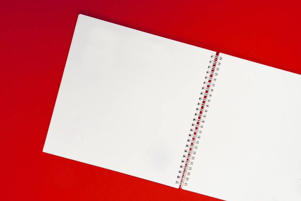 close up of open notebook on spring lying on paper background of red color. For design, mockup, copyspace - Foto, imagen