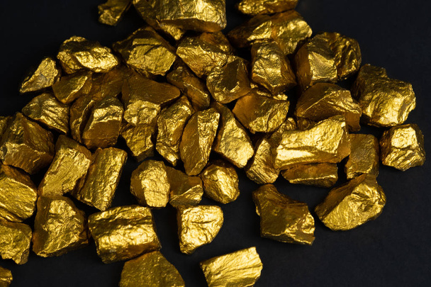 ein Haufen Goldklumpen oder Golderz auf schwarzem Hintergrund, Edelstein oder Goldklumpen, Finanz- und Geschäftsidee. - Foto, Bild