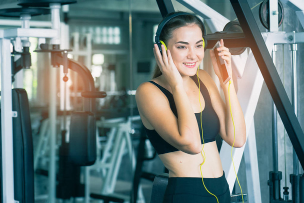 Woman Listening Music, Doing Workout Exercises.Relaxing After Fitness Training in gym.She smile and happy. - Foto, Bild