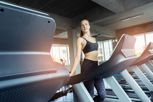 Cute young woman exercising on  treadmill at a gym.Active young woman running on treadmill. smile and funny emotion. - Foto, Imagem