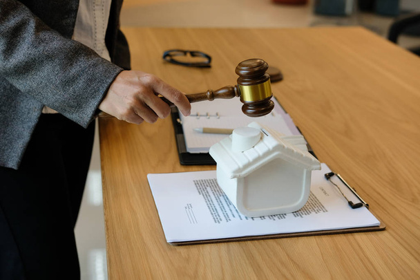 advocaat met rechter hamer kloppen huis model met recht documentat rechtszaal. onroerend goed geschil & eigenschap veiling concept - Foto, afbeelding