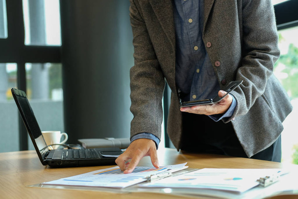 Mann arbeitet Organisationsplan mit Smartphone. Geschäftsmann analysiert Dokument im Coworking Office am Arbeitsplatz - Foto, Bild