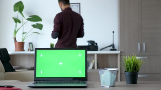 Laptop with an isolated chroma green screen on the desk - Materiał filmowy, wideo