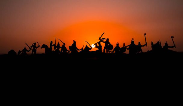 Medieval battle scene with cavalry and infantry. Silhouettes of figures as separate objects, fight between warriors on sunset foggy background. Selective focus - Photo, Image